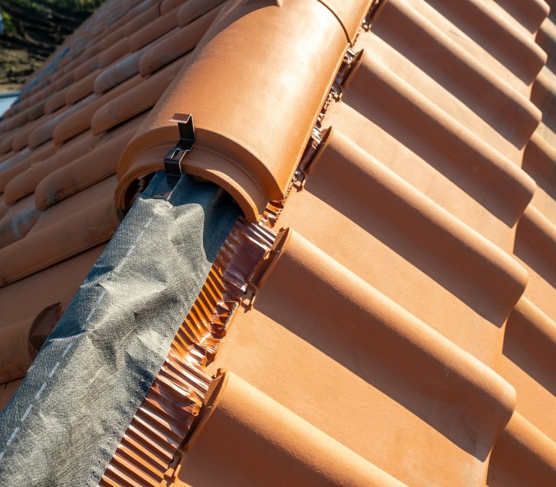 Closeup of yellow ceramic roofing ridge tiles on top of residential building roof under construction